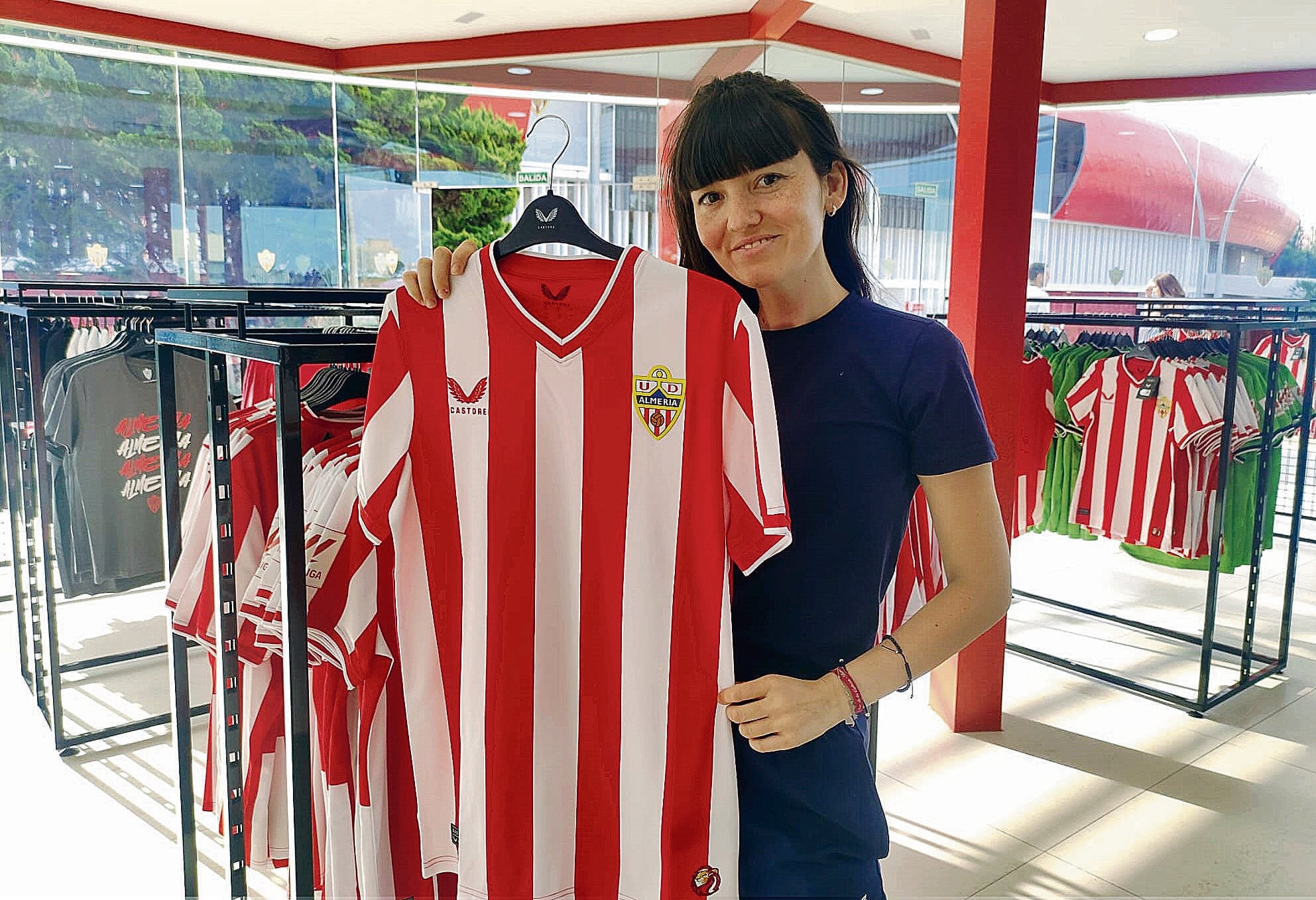 Rocío Cazorla, empleada de la tienda del Almería, enseña la nueva camiseta rojiblanca.