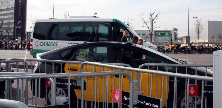 Un taxi esperando clientes en el Mobile World Congress junto a un autobus contratado por una empresa privada  