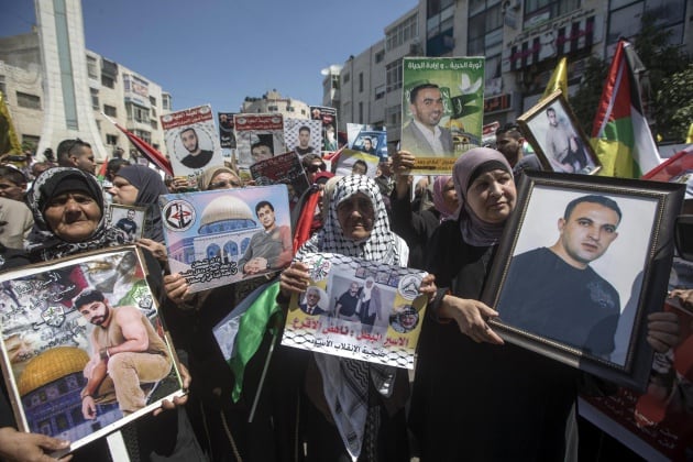 Palestinos sostienen carteles con imágenes de sus parientes encarcelados en prisiones israelíes, en la ciudad cisjordana de Ramala, hoy, 17 de abril de 2017. Alrededor de 1.500 presos palestinos en cárceles israelíes están desde esta medianoche en huelga 