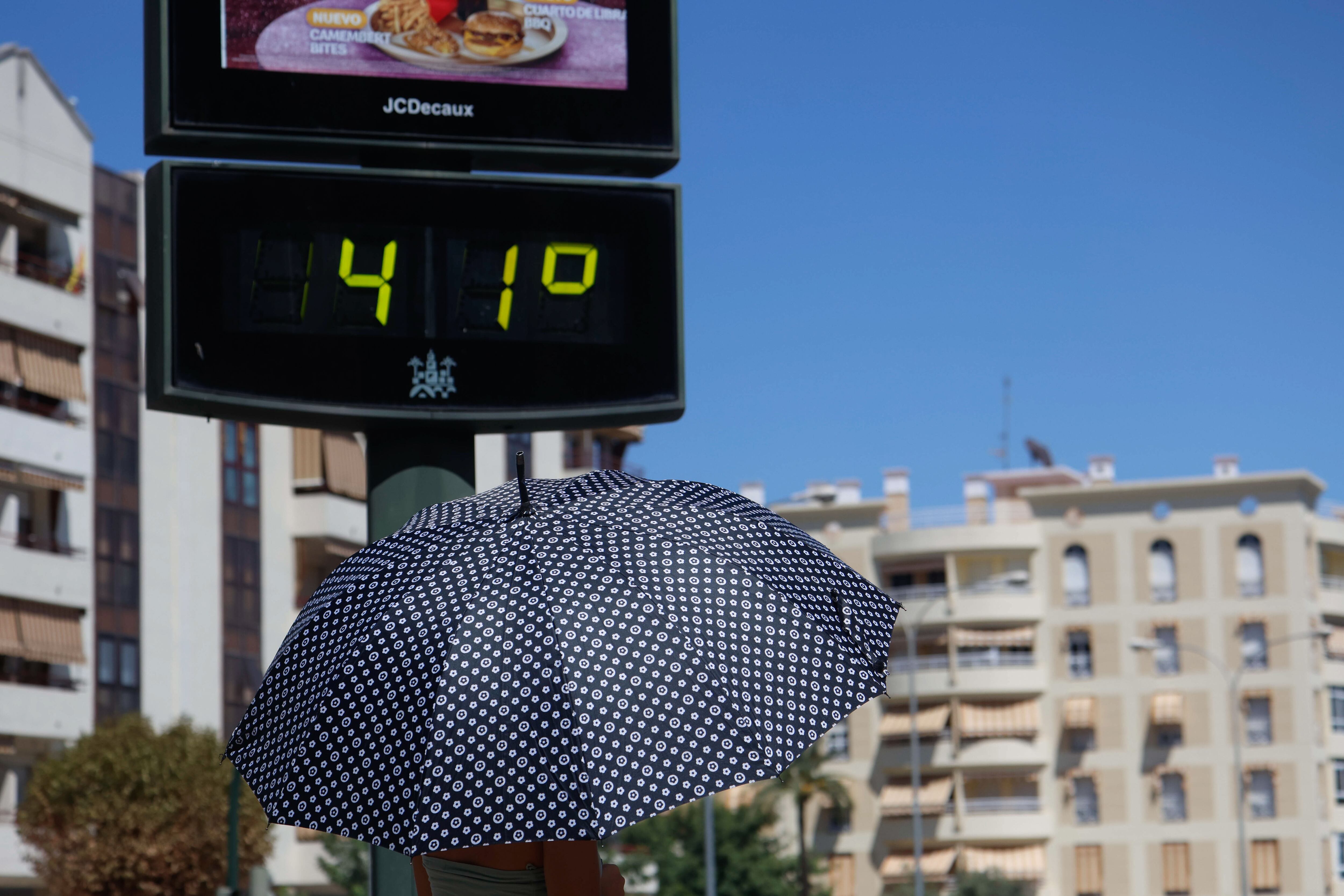 CÓRDOBA, 06/08/2025.- Una persona se protege del sol miemntras camina junto a un termómetro que marca 41 grados e Córdoba este miércoles, una jornada marcada por las altas temperaturas en casi todo el país. EFE/Salas