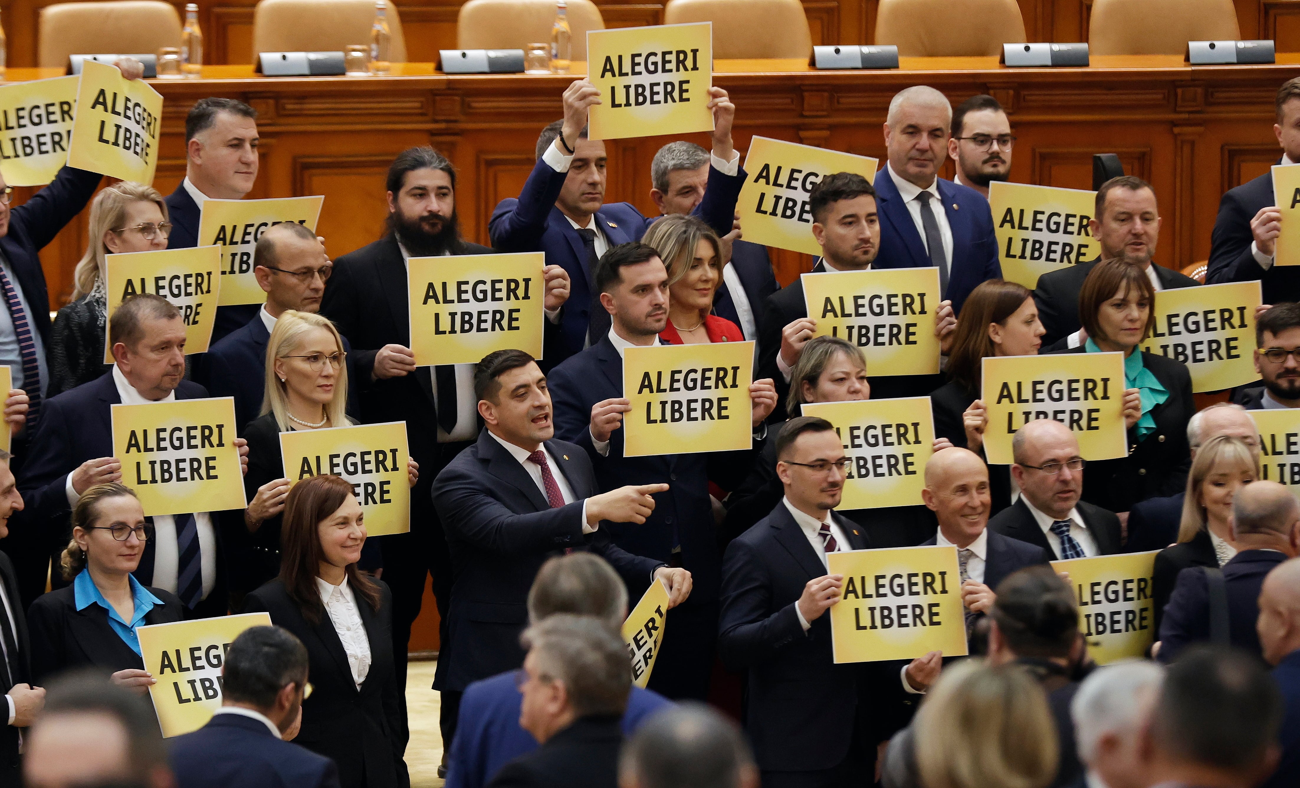 Miembros del partido de extrema derecha AUR muestran en el parlamento rumano carteles contra el nuevo Gobierno de coalición