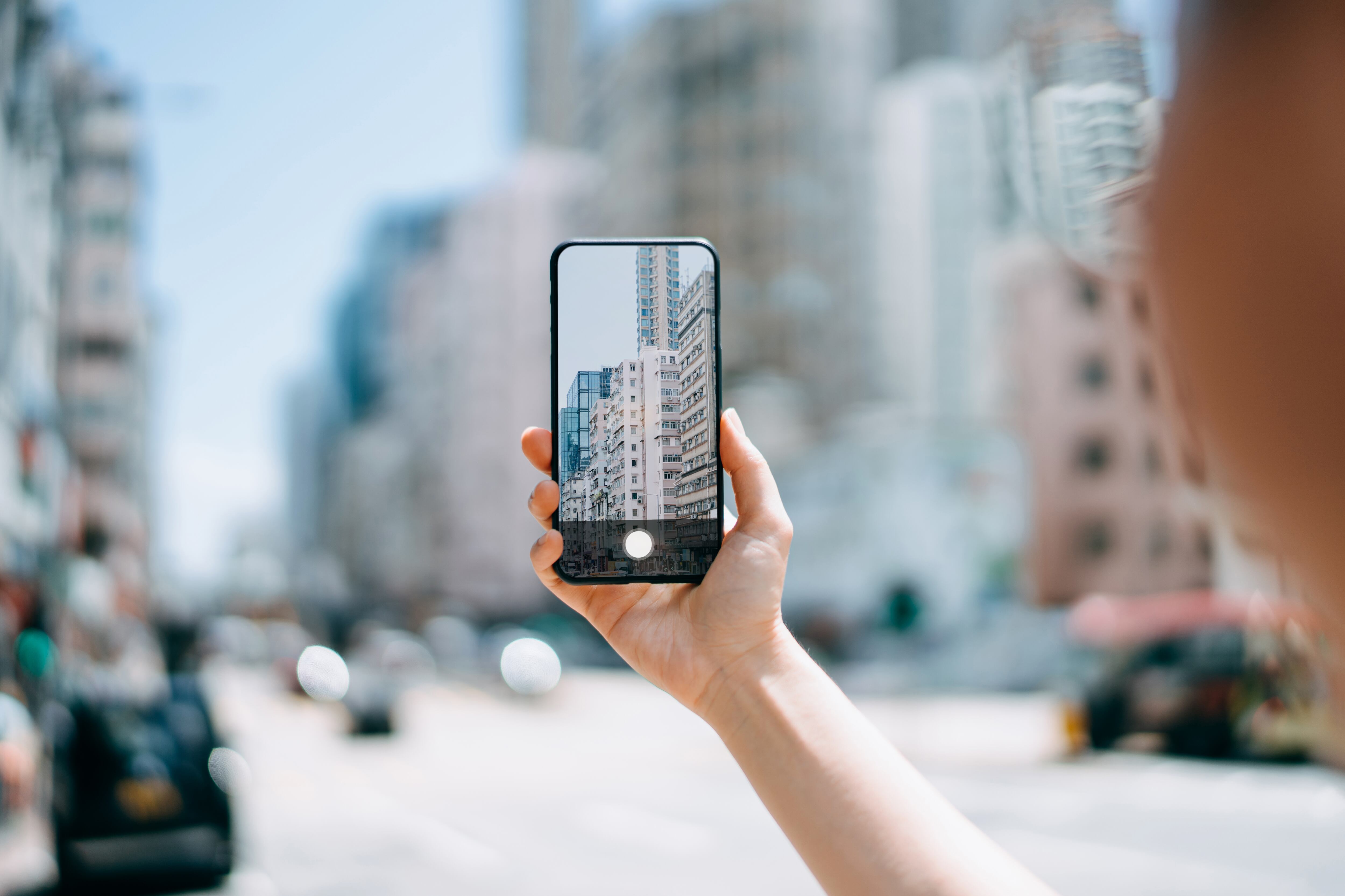 Close up of woman&#039;s hand taking a photo of local city street view in Hong Kong with smartphone