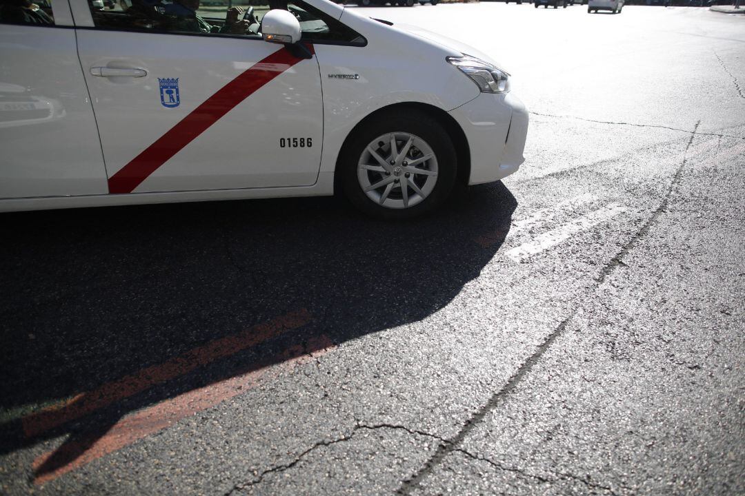 Una taxi pasa por encima de una línea naranja que indica restricción al tráfico en el centro de Madrid