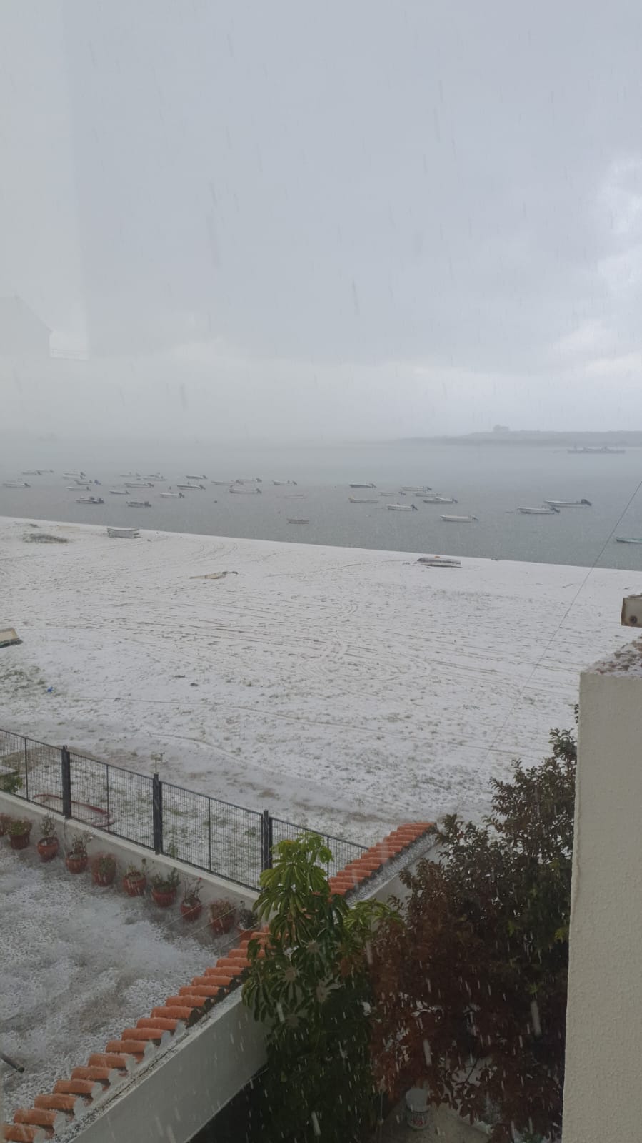 La playa y algunas embarcaciones cubiertas por el granizo