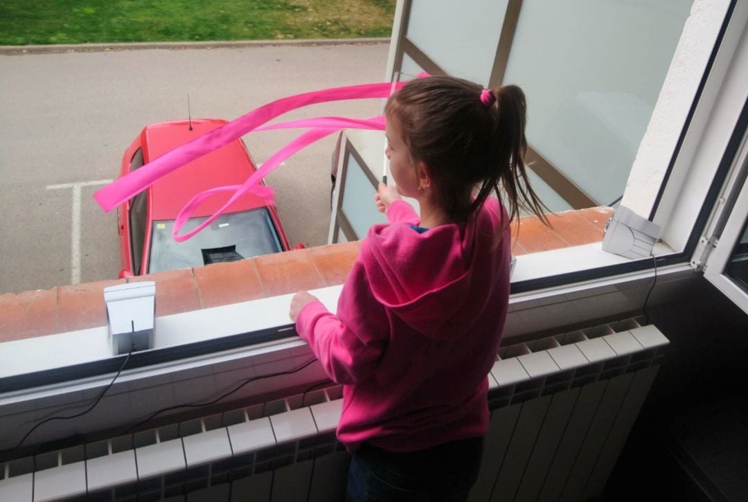 Una nena mentre balla la cançó a la finestra de casa seva a Ripoll aquest dissabte 28 de març de 202