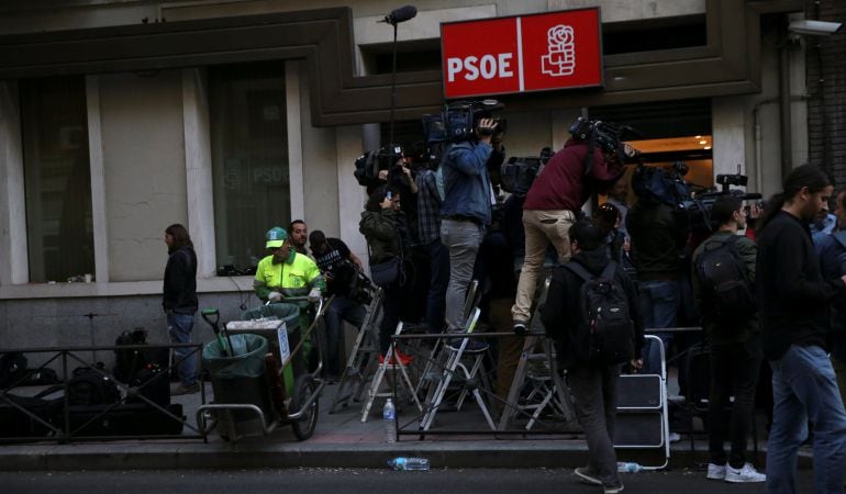 Un limpiador municipal, junto a los periodistas a las afueras de la sede madrileña del PSOE.