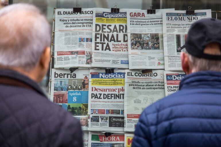 Dos hombres ante un puesto de prensa con la noticia del desarme de ETA en la portada de los periódicos