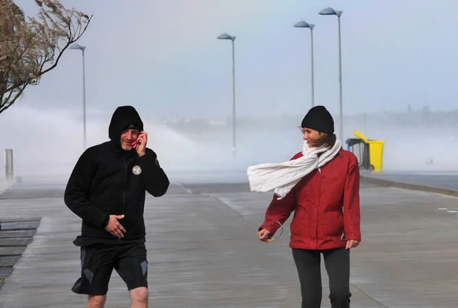 Dos personas pasean por el puerto de Roses, en Girona, bajo un fuerte viento