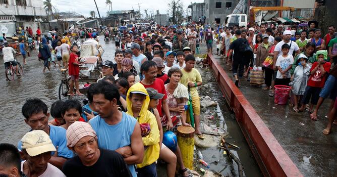 Miles de personas forman interminables colas para recibir la ración de arroz y agua que las autoridades filipinas han establecido para cada afectado en los lugares habilitados para el reparto en Tacloban.