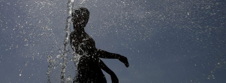 Una joven se refresca a una fuente en la calle