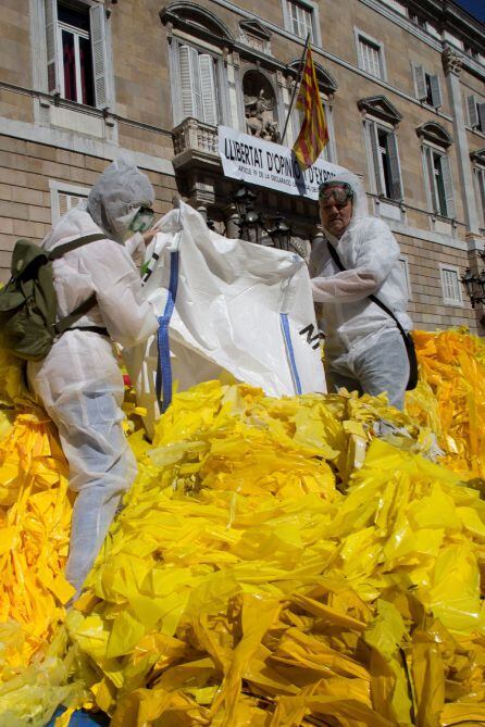 Miembros de la brigada de limpieza d&#039;Els Segadors del Maresme, que se dedican a quitar lazos amarillos de lugares públicos, los depositan frente a la fachada principal del Palau de la Generalitat.