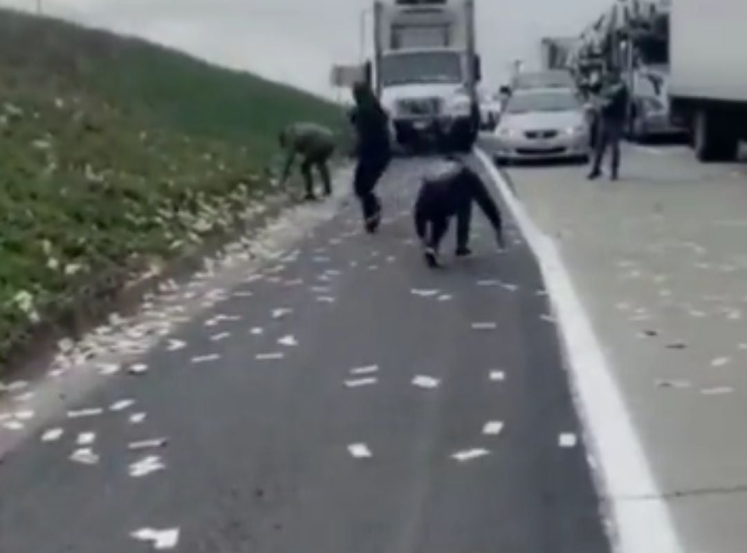 Conductores recogen dinero del suelo que cae de un coche blindado.