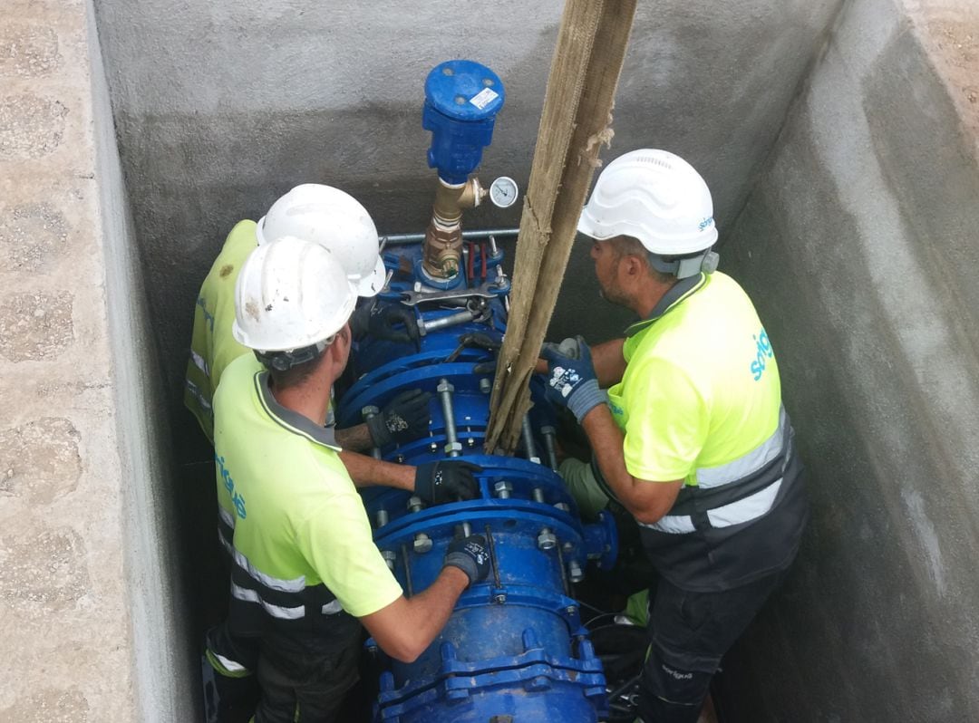 Tres operarios trabajan en una tubería de agua.