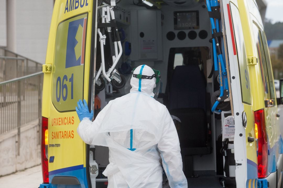 Un trabajador sanitario totalmente protegido cierra la puerta de una ambulancia tras recoger a un anciano