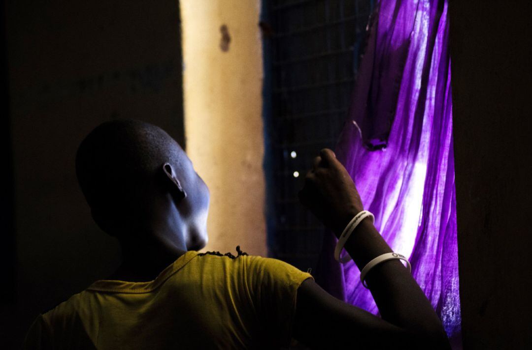 Una mujer mira por la ventana durante el confinamiento en el centro de estancia temporal de Kalas, en Uganda.