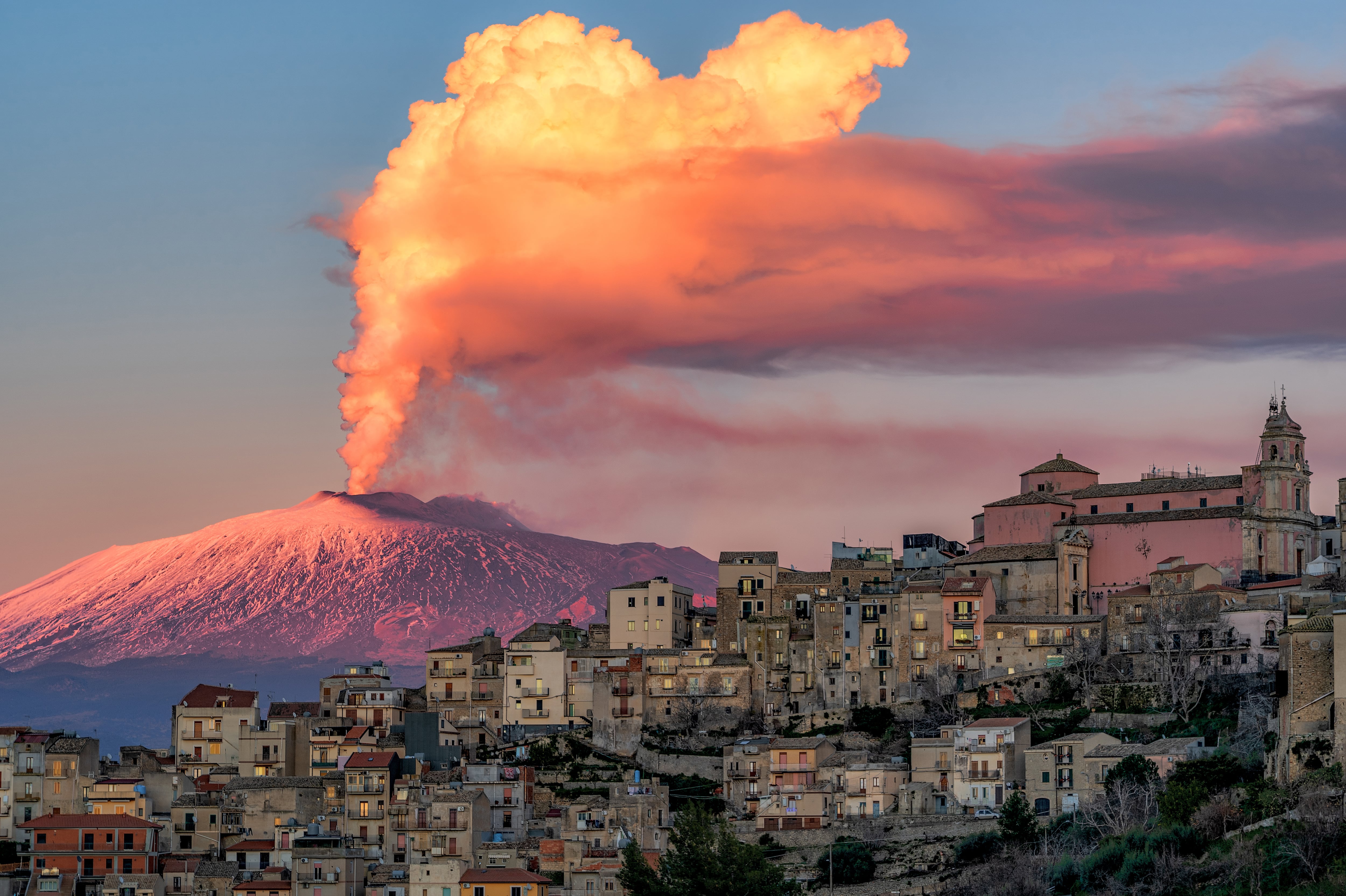 Cityscape of Centuripe and in the background the erupting Volcano Etna. Sicily. Italy. Europe. (Photo by: Antonio Treccarichi/REDA/Universal Images Group via Getty Images)