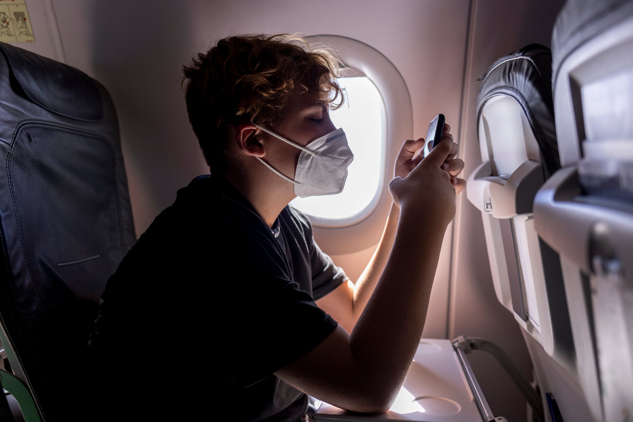 Joven con mascarilla en un avión