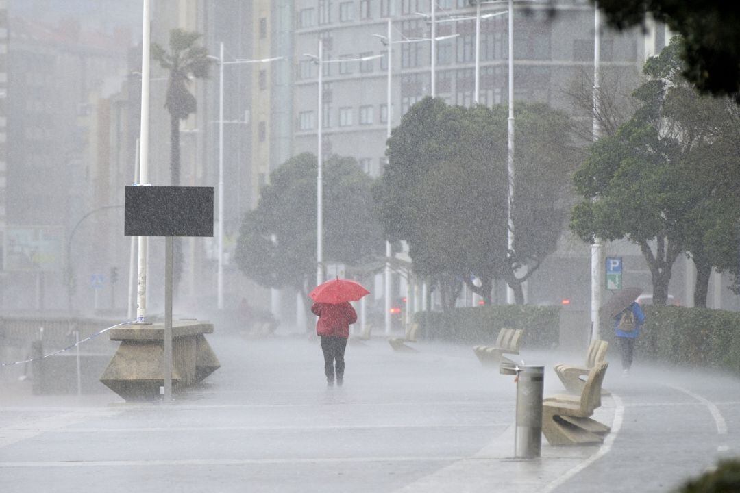 Dos mujeres caminan bajo la lluvia en el paseo marítimo de A Coruña.