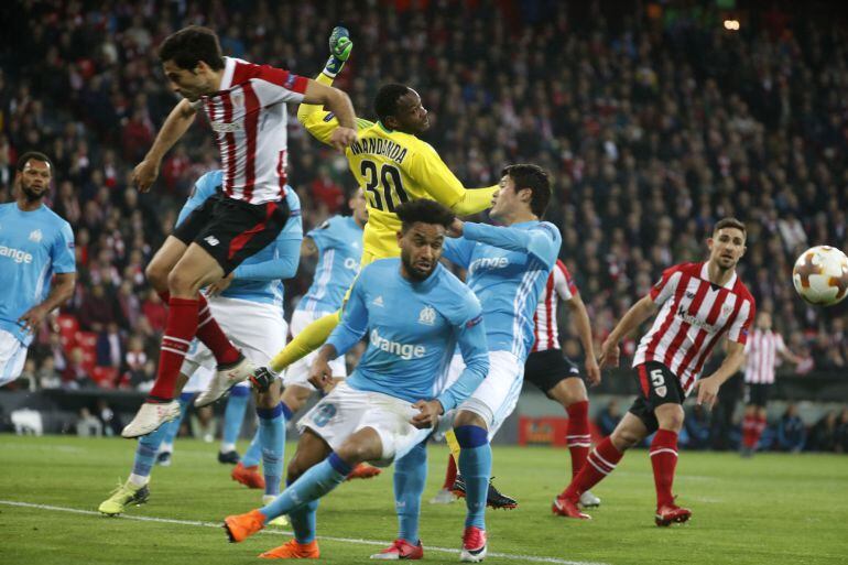 El jugador del Athletic de Bilbao Etxeita disputa un balón con el portero del Olympique de Marsella, Steve Mandanda durante el partido de vuelta de octavos de final de la Liga Europa que el Athletic de Bilbao y Olympique de Marsella disputan en el estadio de San Mamés.