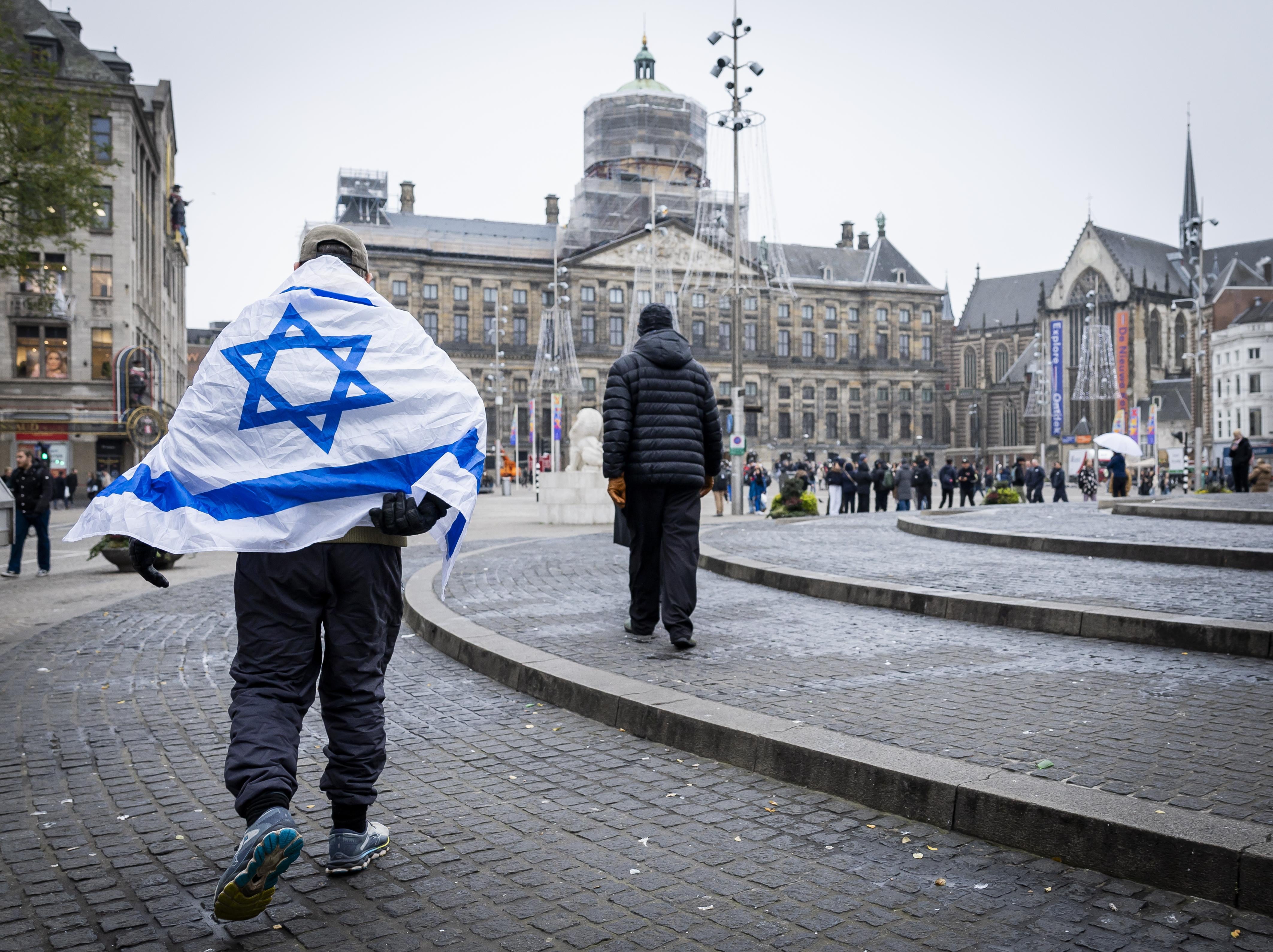 Un hombre lleva una bandera de Israel cerca de la Plaza Dam de Ámsterdam después de los incidentes de la pasada noche