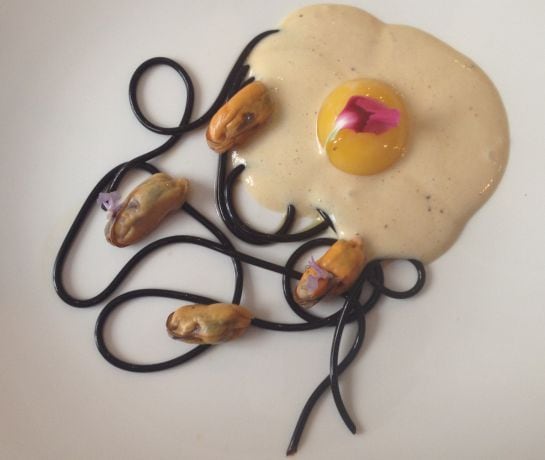 Huevo macerado en sal, espuma de carbonara, mejillones y espagueti de ajo negro.