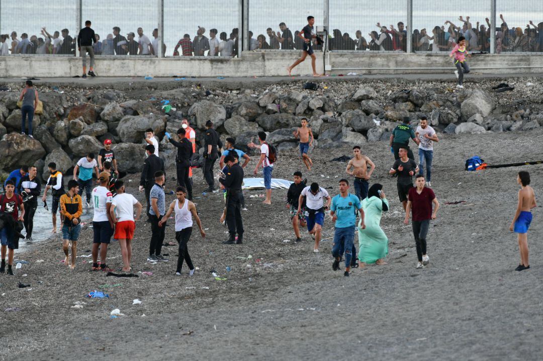 Personas migrantes caminan por la playa del Tarajal, a 17 de mayo.