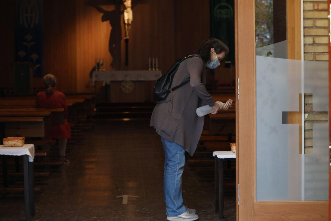 Una mujer utiliza el gel hidroalcohólico en la entrada de una parroquia.