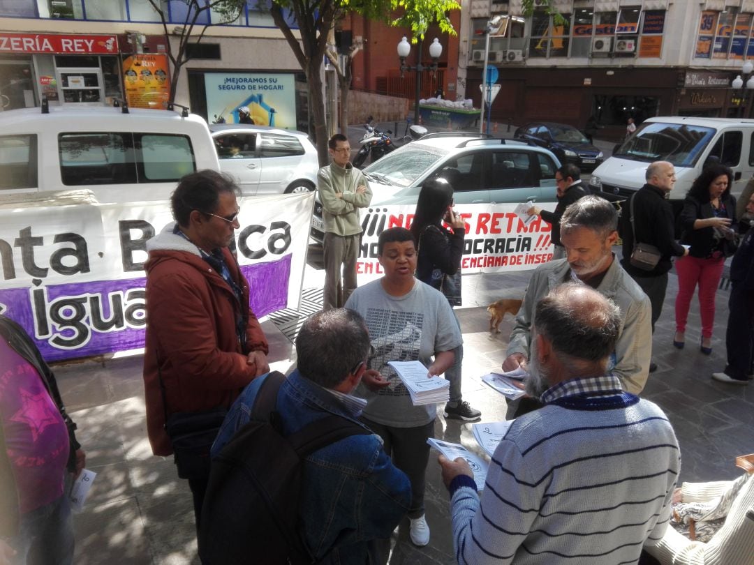 Miembros de Marea Roja protestan con pancartas ante el PROP de Alicante para exigir acabar con las demoras en los pagos de la Renta Valenciana de Inclusión.