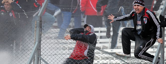 Dos hinchas se cuelgan de una de las vallas del estadio bonaerense