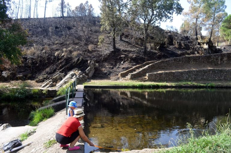 Una turista comprueba el estado del agua en la piscina natural de Hoyos