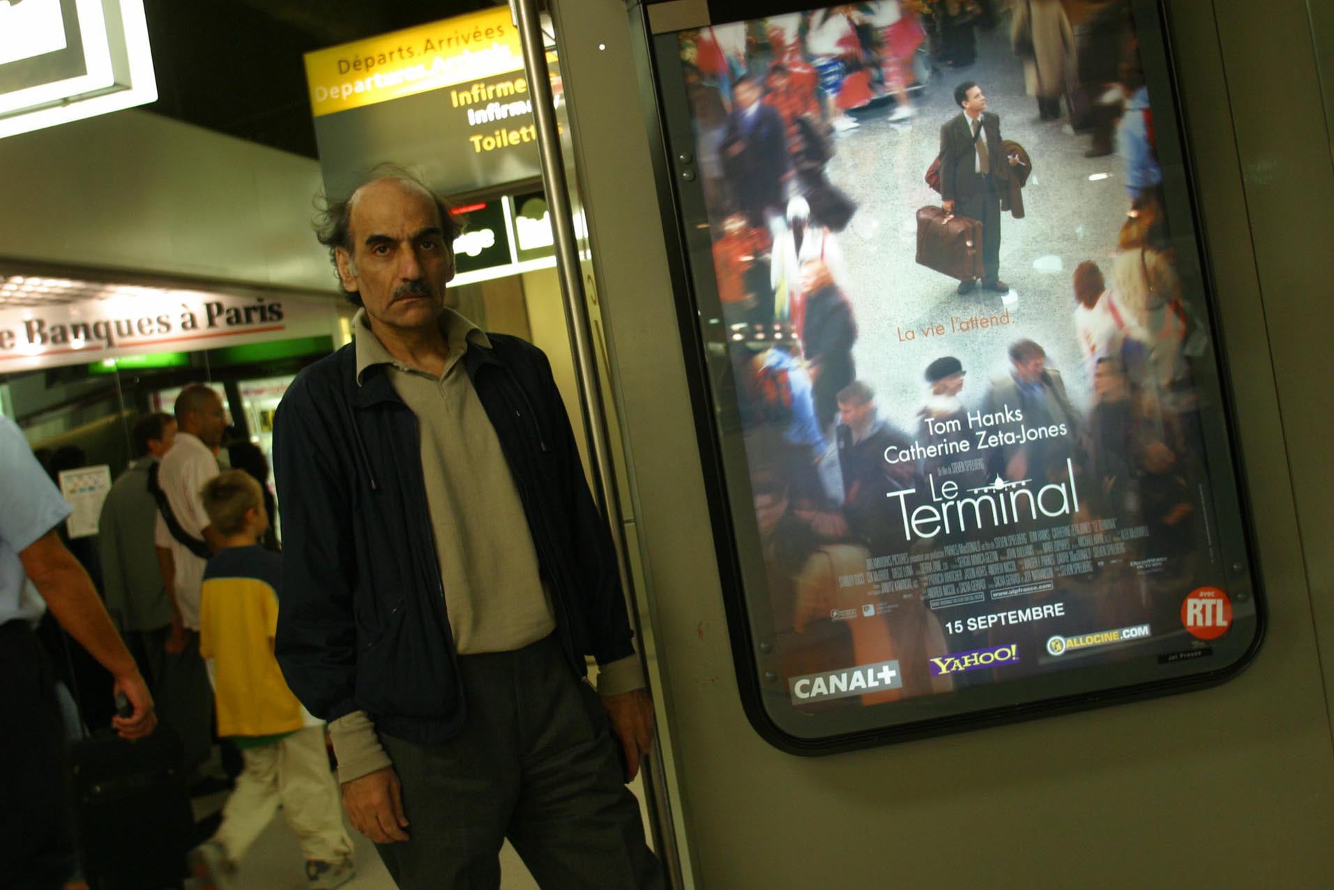 Karimi Nasseri en el aeropuerto frente al cartel de su película.