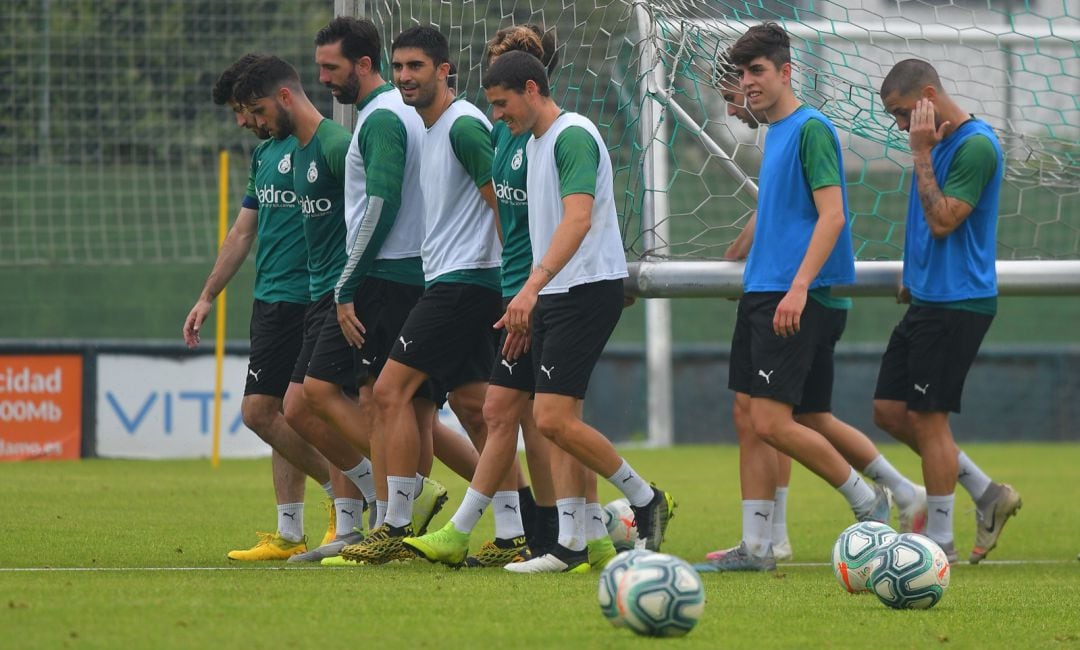 Íñigo, con peto azul, en primer plano, cargando con una portería junto a los jugadores del primer equipo en la sesión del lunes.