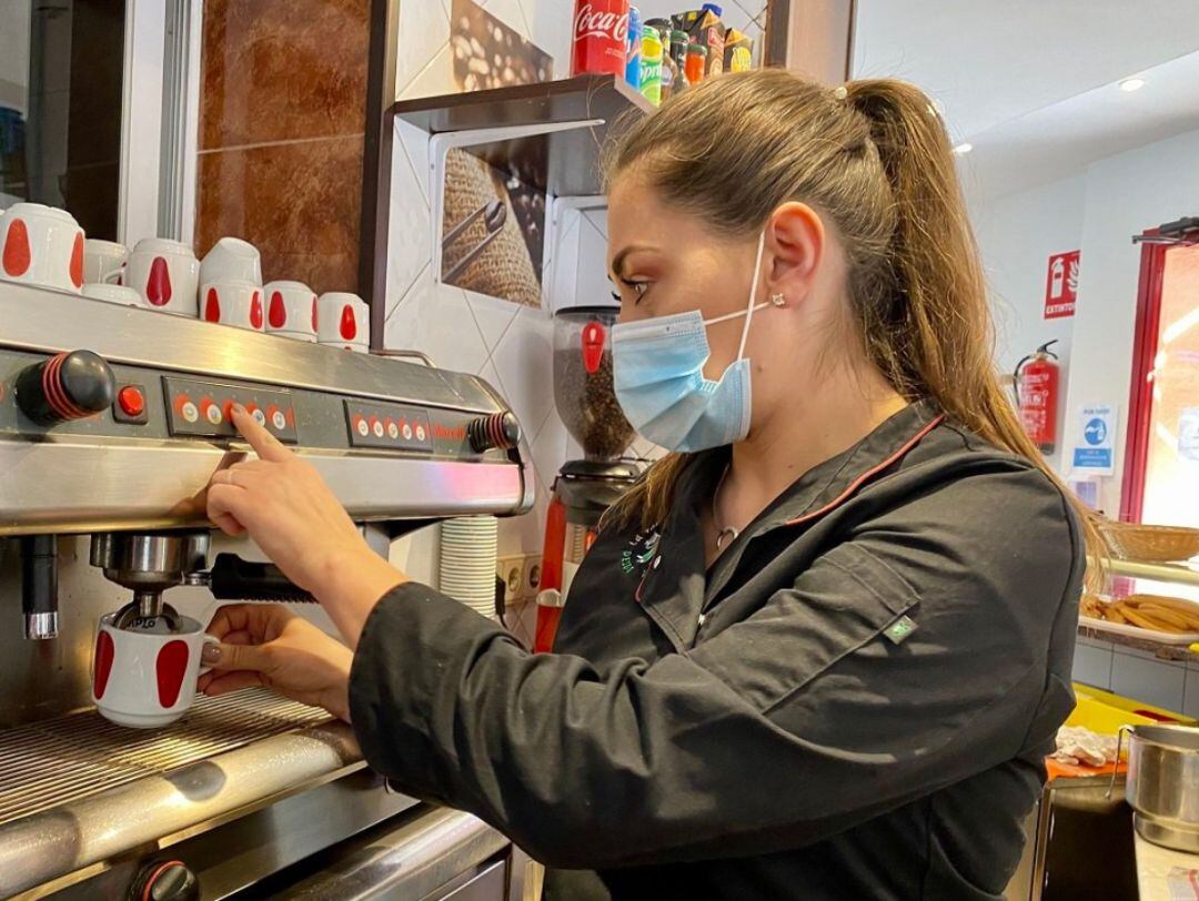 Una mujer sirve un café en un bar.