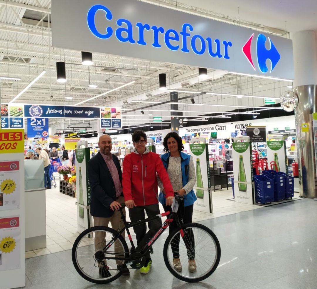 Pablo Celemín Cortés, junto a los representantes de Carrefour Segovia y Radio Segovia en el momento de la entrega de la bicicleta