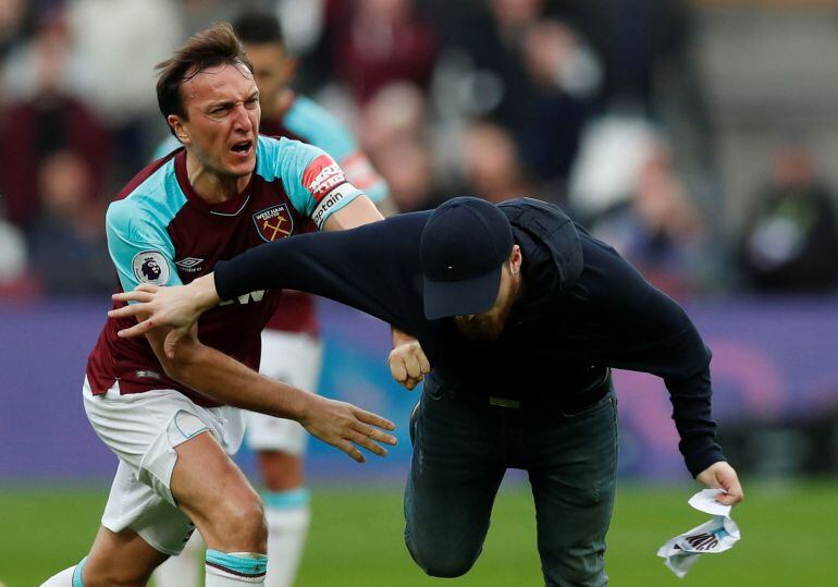 Mark Noble, del West Ham, intenta detener a uno de los espectadores que saltó al césped en el partido ante el Burnley.