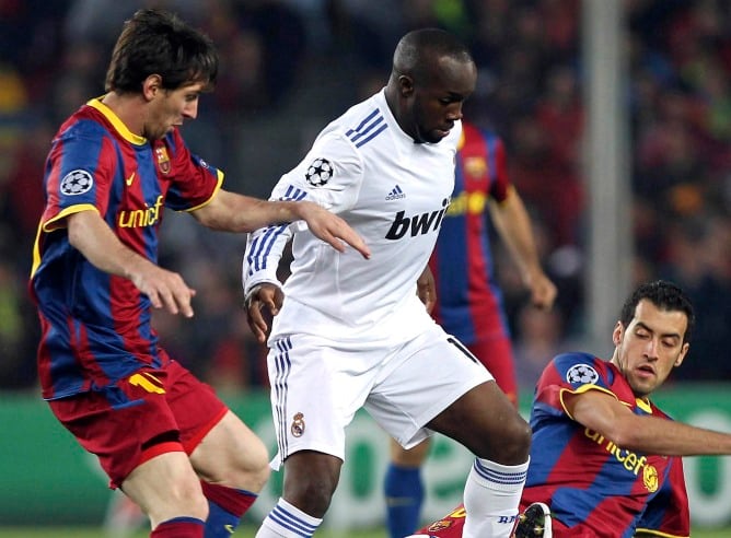 El centrocampista francés del Real Madrid Lass Diarra controla el balón ante los jugadores del F.C. Barcelona, Sergio Busquets y el argentino Lionel Messi