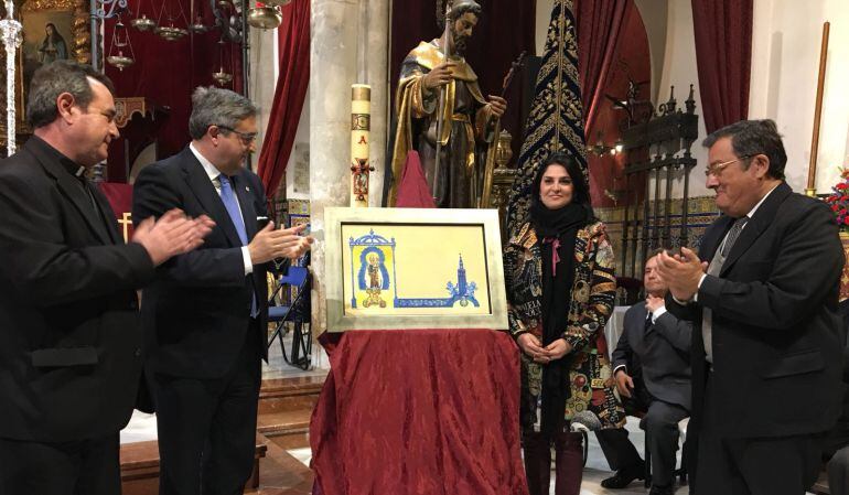 De izquierda a derecha, junto a la pintura presentada, el párroco de San Julián, el hermano mayor de La Hiniesta, José Antonio Romero; la pintora Nuria Barrera y el presidente del Consejo de Cofradías, Joaquín Sainz de la Maza