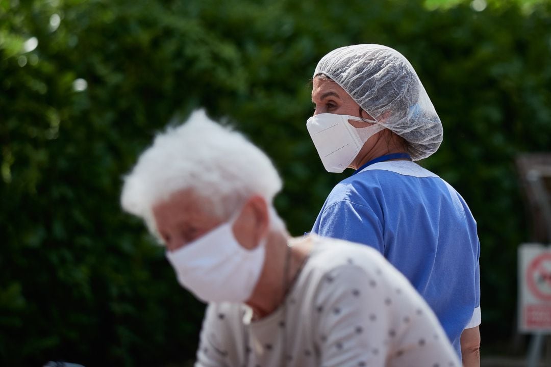 Una residente y una trabajadora sanitaria, ambas protegidas con mascarilla.