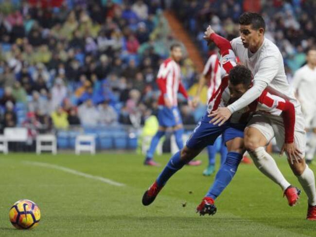 El defensa brasileño del Sporting Douglas Pereira disputa el balón ante el centrocampista colombiano del Real Madrid James Rodríguez.