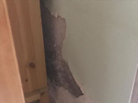 Una vecina muestra una pared del interior de su vivienda