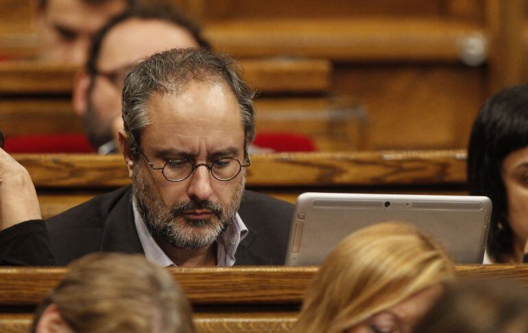 El diputado de la CUP Antonio Baños escucha la intervención del candidato de Junts pel Si a la presidencia de la Generalitat, Artur Mas, en el debate de investidura del nuevo presidente