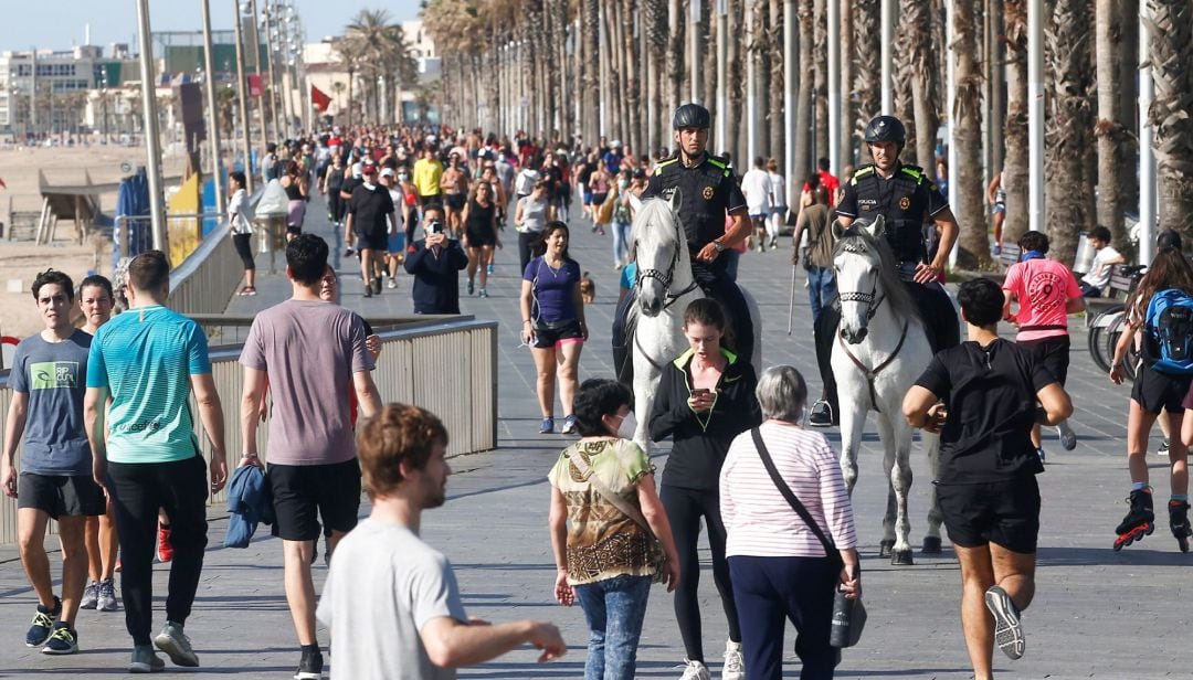 Dos policías a caballo patrullan entre los ciudadanos que pasean por Paseo Marítimo de Barcelona.