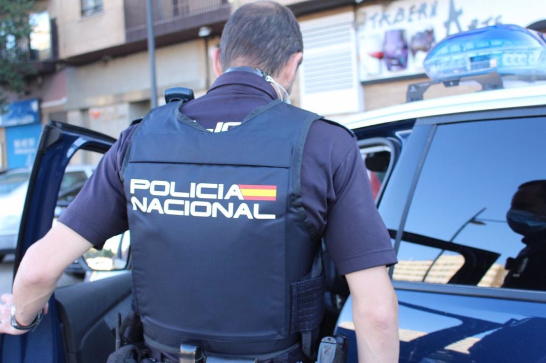 Un agente de la Policía Nacional se dispone a entrar en el coche patrulla