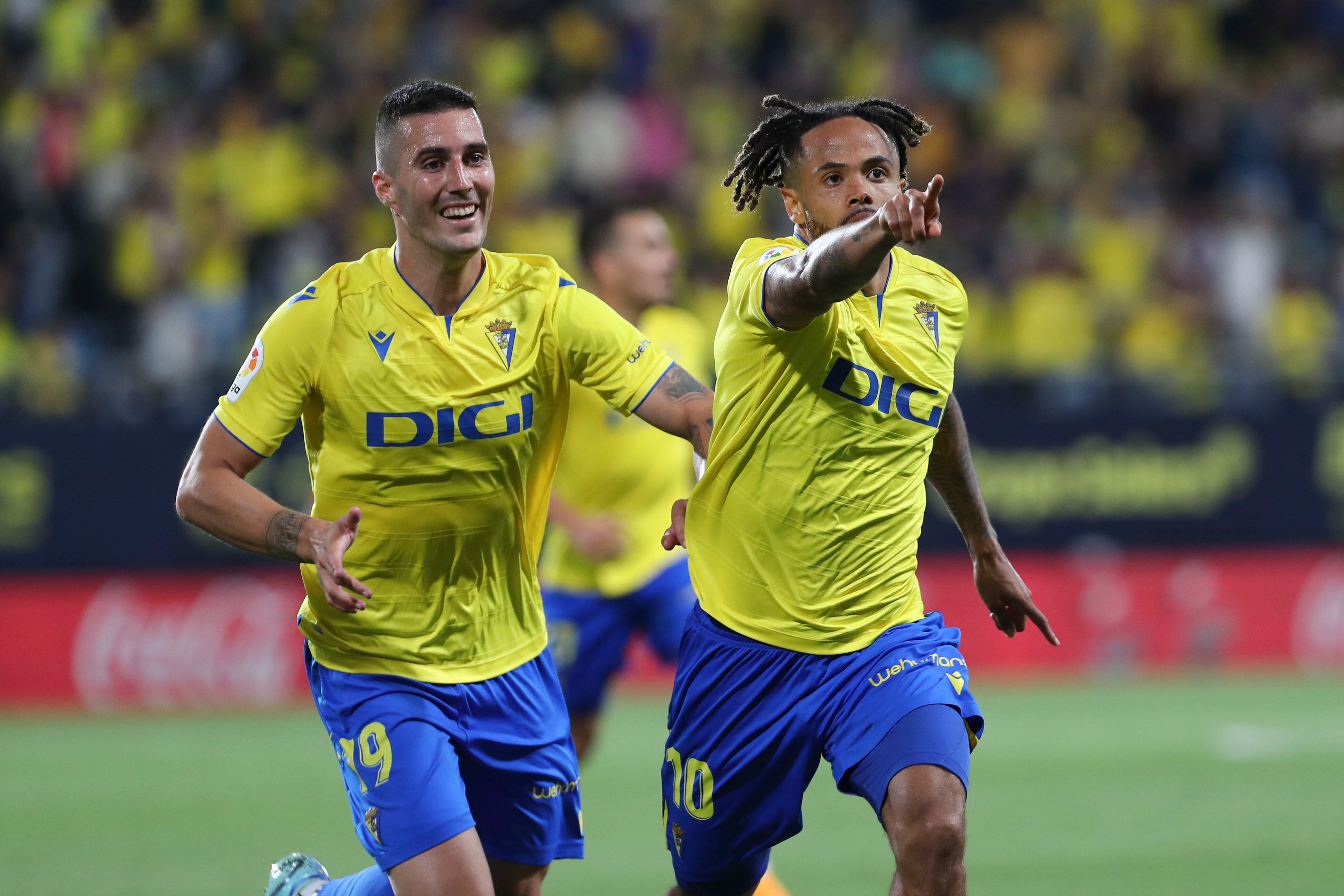 CÁDIZ, 19/05/2023. Los jugadores del Cádiz, el belga Theo Bondonga (d) y Sergi Guardiola, celebran el primer gol del equipo gaditano durante el encuentro correspondiente a la jornada 35 de primera división que disputan hoy viernes frente al Valladolid en el estadio Nuevo Mirandilla, en Cádiz. EFE/Román Ríos.
