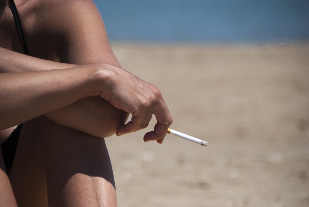 Una mujer fuma en la playa