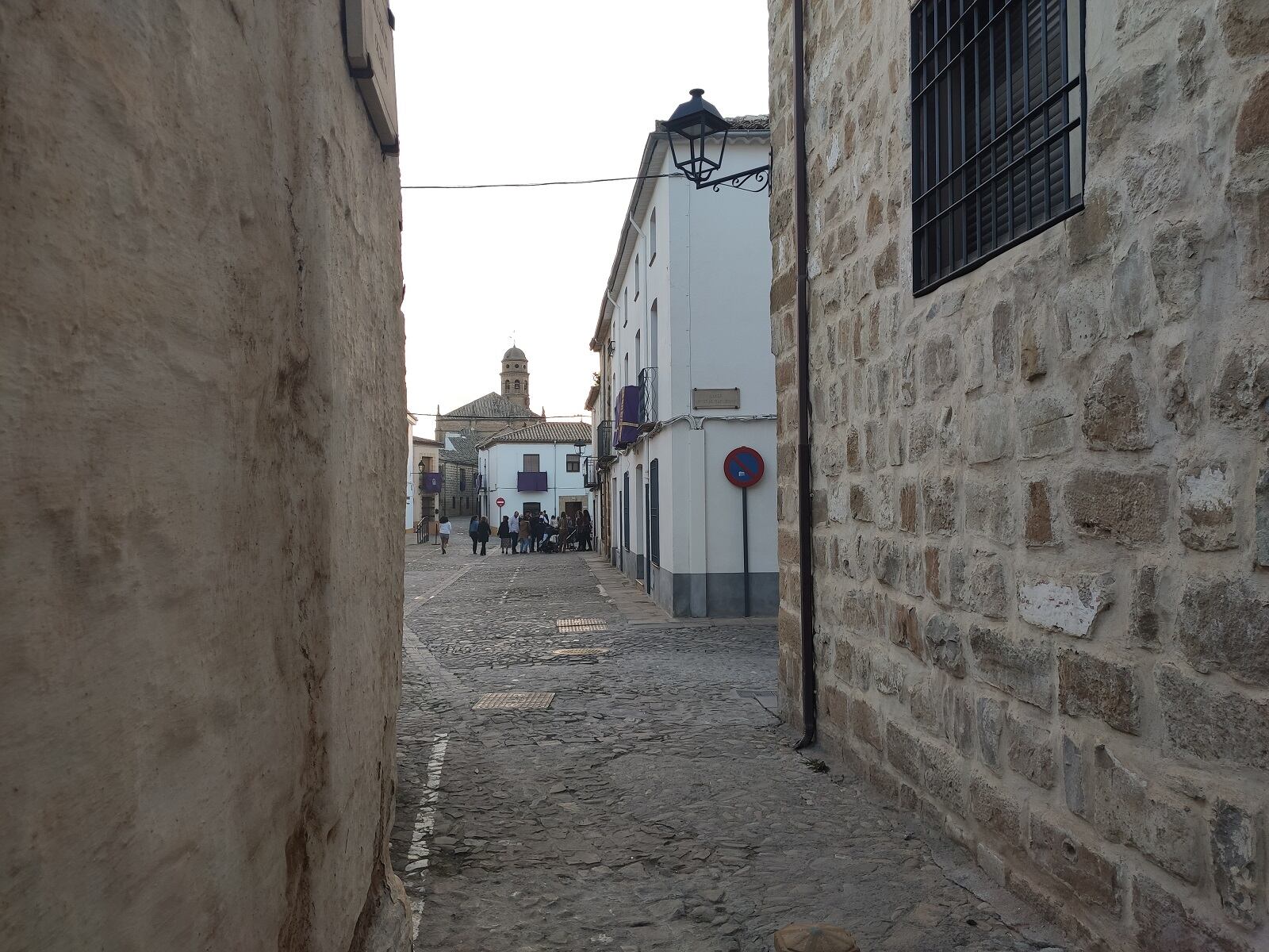 Un callejón en la ciudad de Baeza, al atardecer, con turistas al fondo