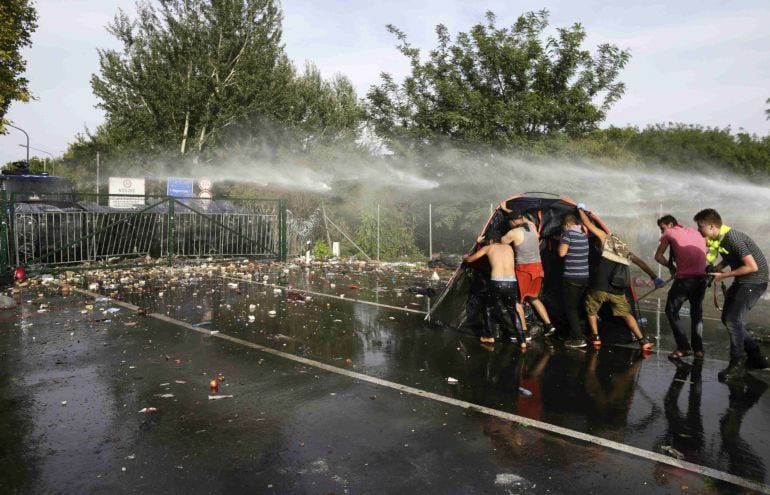 Migrants protest as Hungarian riot police fires tear gas and water cannon at the border crossing with Serbia in Roszke, Hungary September 16, 2015. Hungarian police fired tear gas and water cannon at protesting migrants demanding they be allowed to enter 