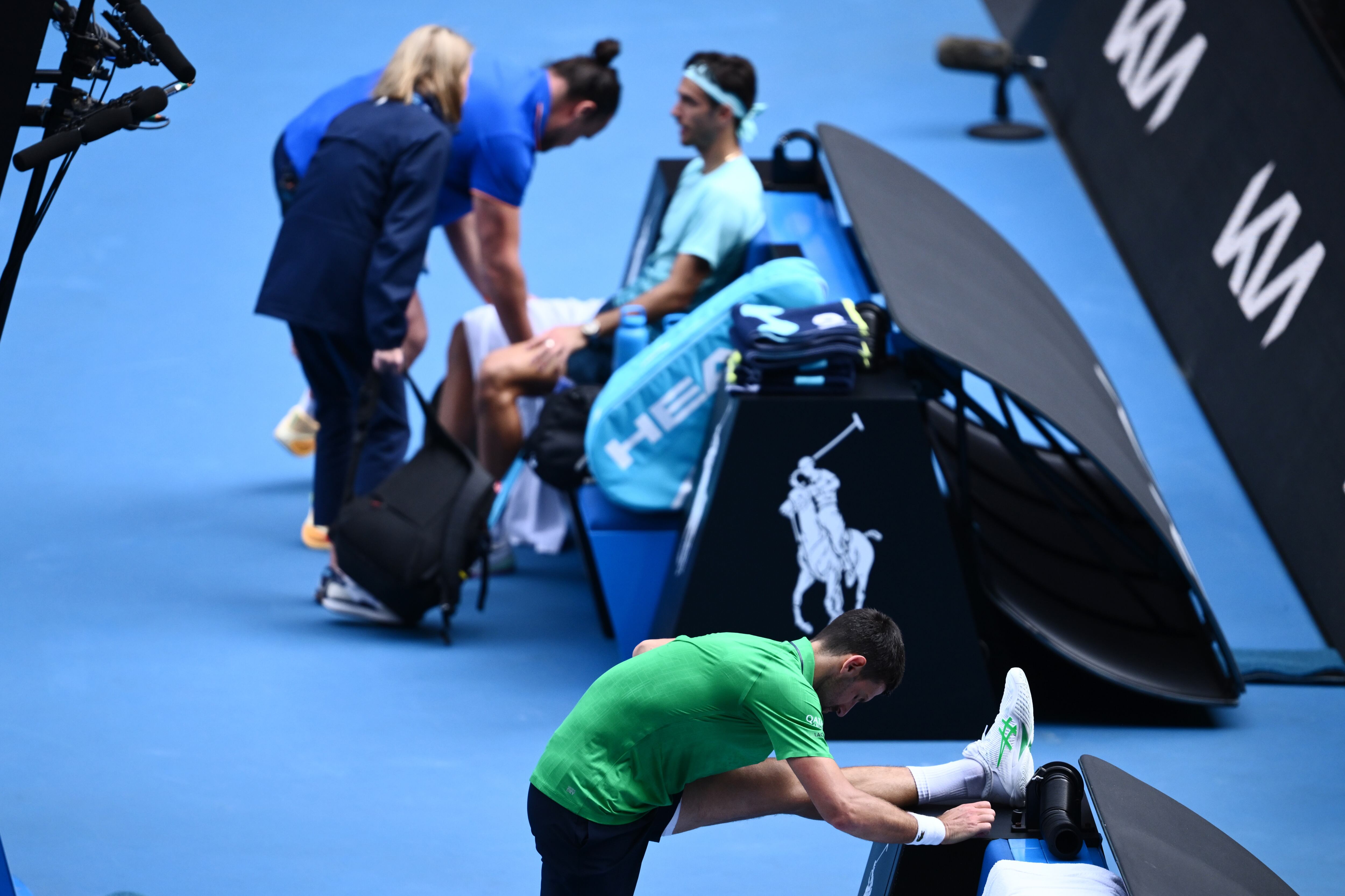 Novak Djokovic estira mientras los médicos exploran la lesión de Lorenzo Musetti