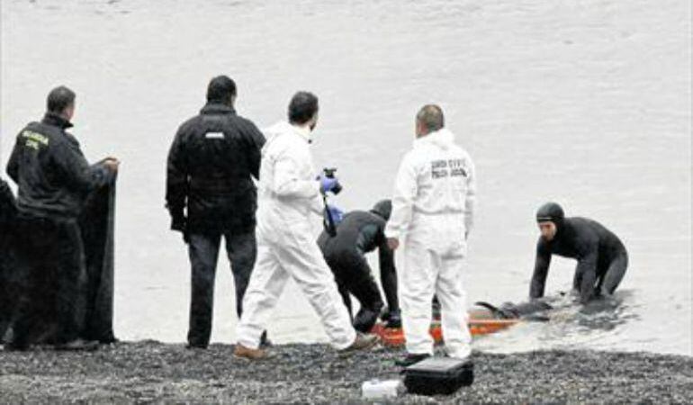 Agentes de la Guardia Civil recogen uno de los cadáveres aparecidos en la playa del Tarajal