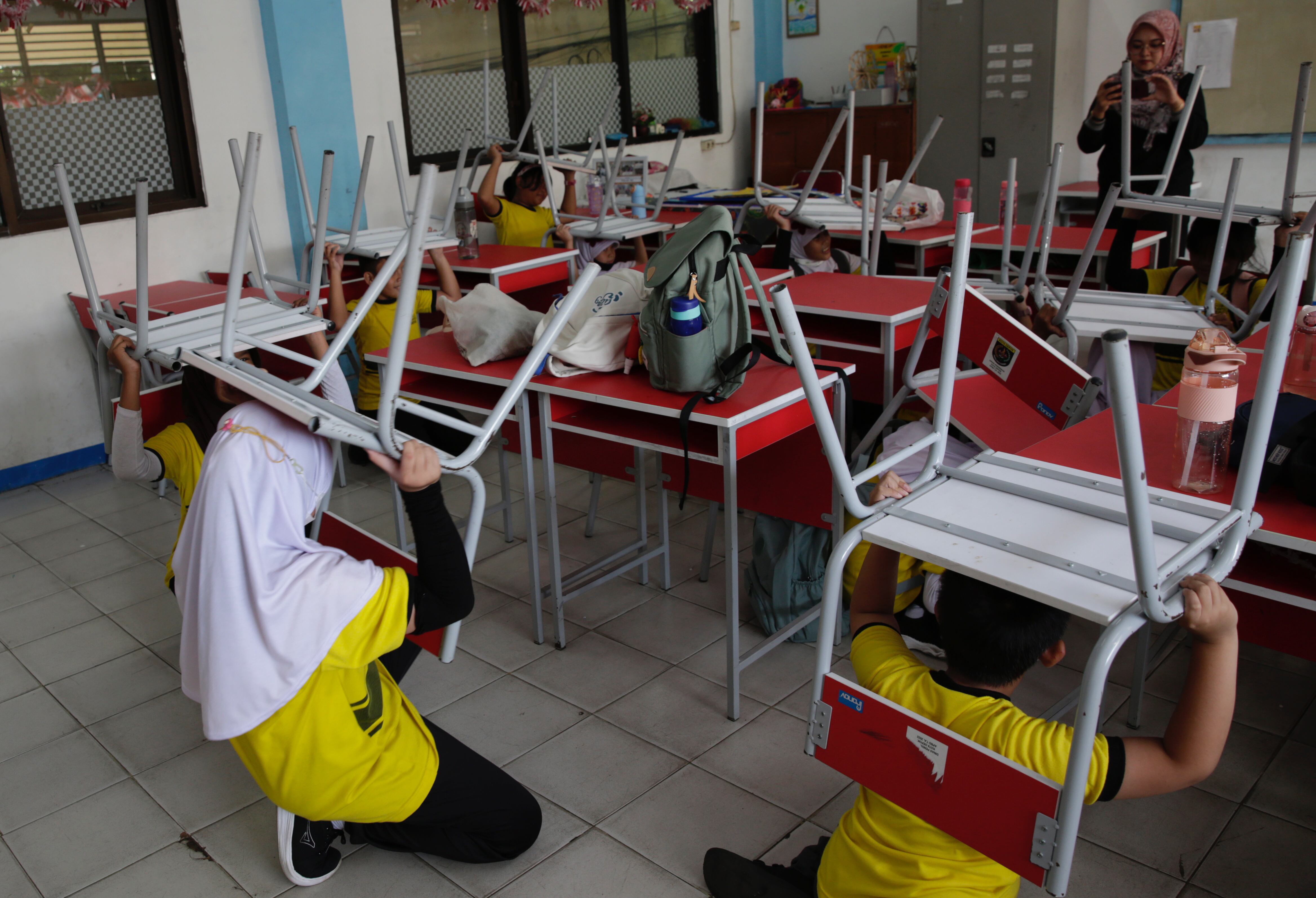 Depok (Indonesia), 20/07/2023.- School students lift chairs as they take cover during a disaster simulation at Anyelir 1 elementary school in Depok, Indonesia, 20 July 2023. The National Disaster Management Agency noted that there were 988 natural disasters that hit Indonesia from January to May 2023, 11 of which were earthquakes, and dozens of fires and floods in various cities in Indonesia. (Terremoto/sismo, Inundaciones) EFE/EPA/ADI WEDA
